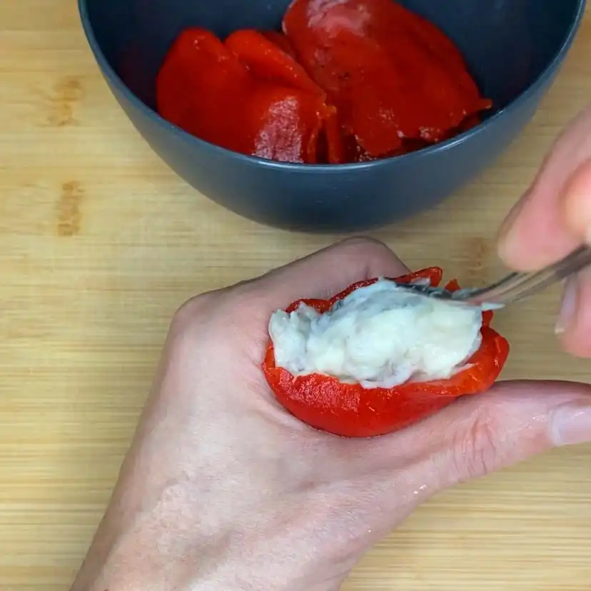 un pimiento del piquillo siendo rellenado, como parte de la receta de pimientos rellenos de carne