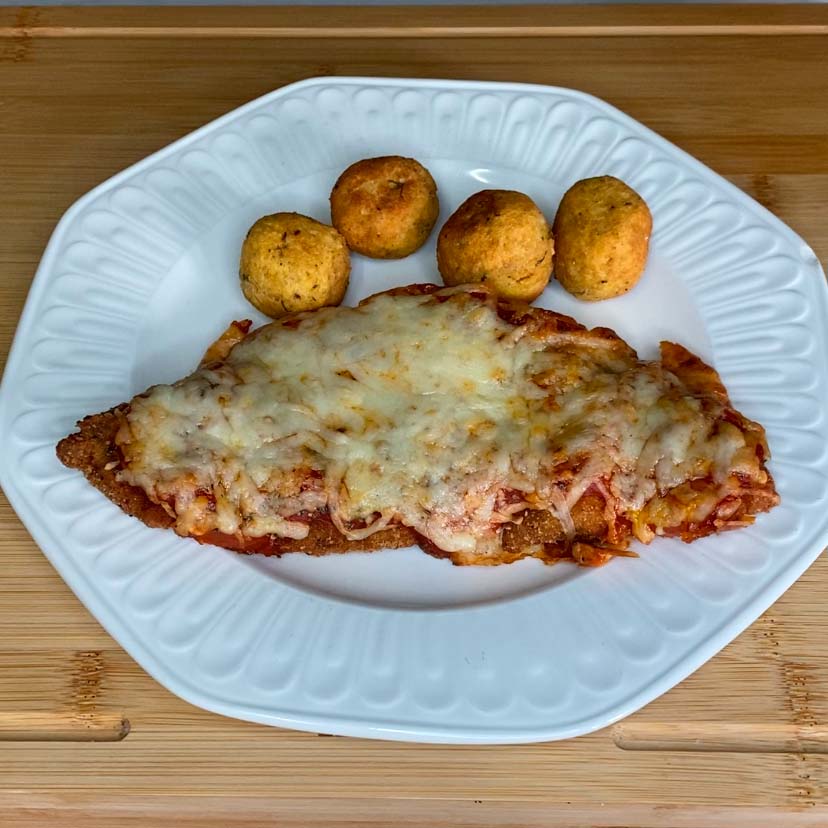 un plato de una milanesa napolitana con una guarnición de huevos tontos